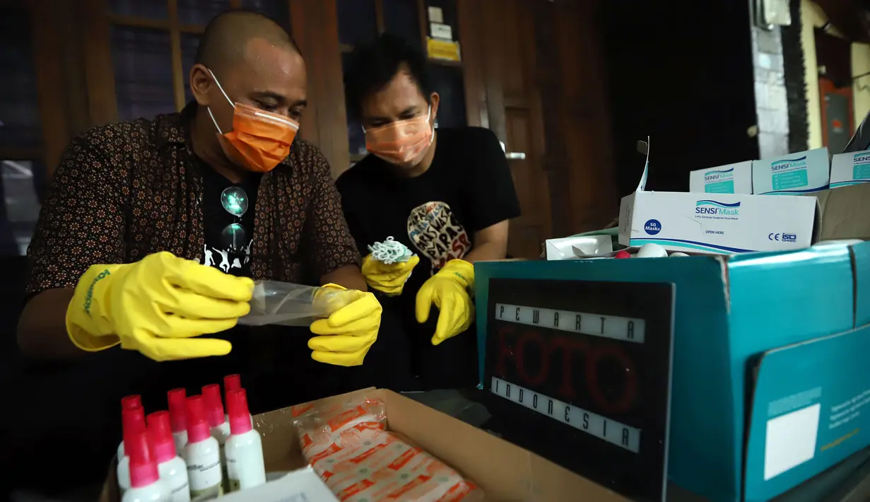 Ketua Pewarta Foto Indonesia (PFI) Reno Esnir (kiri) merapikan masker dan hand sanitizer untuk dibagikan kepada jurnalis foto di Jakarta, Jumat (20/3/2020). Reno menyatakan, langkah ini dilakukan karena jurnalis foto sulit untuk menerapkan work from home (WFH). (Foto: Dok. Pewarta Foto Indonesia)