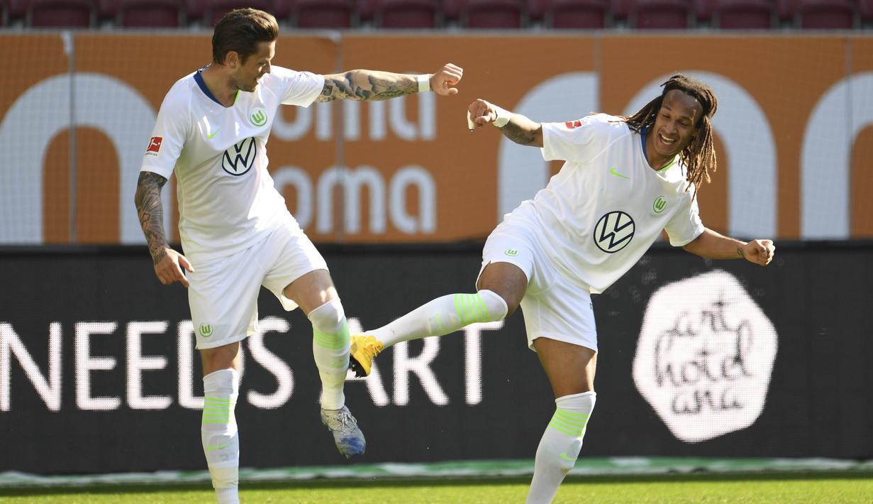 Pemain Wolfsburg, Daniel Ginczek dan Kevin Mbabu merayakan gol yang dicetak ke gawang FC Augsburg pada laga Bundesliga di Augsburg, Sabtu (16/5/2020). Pandemi COVID-19 membuat pemain melakukan selebrasi jaga jarak. (AFP/Tobias Hase)
