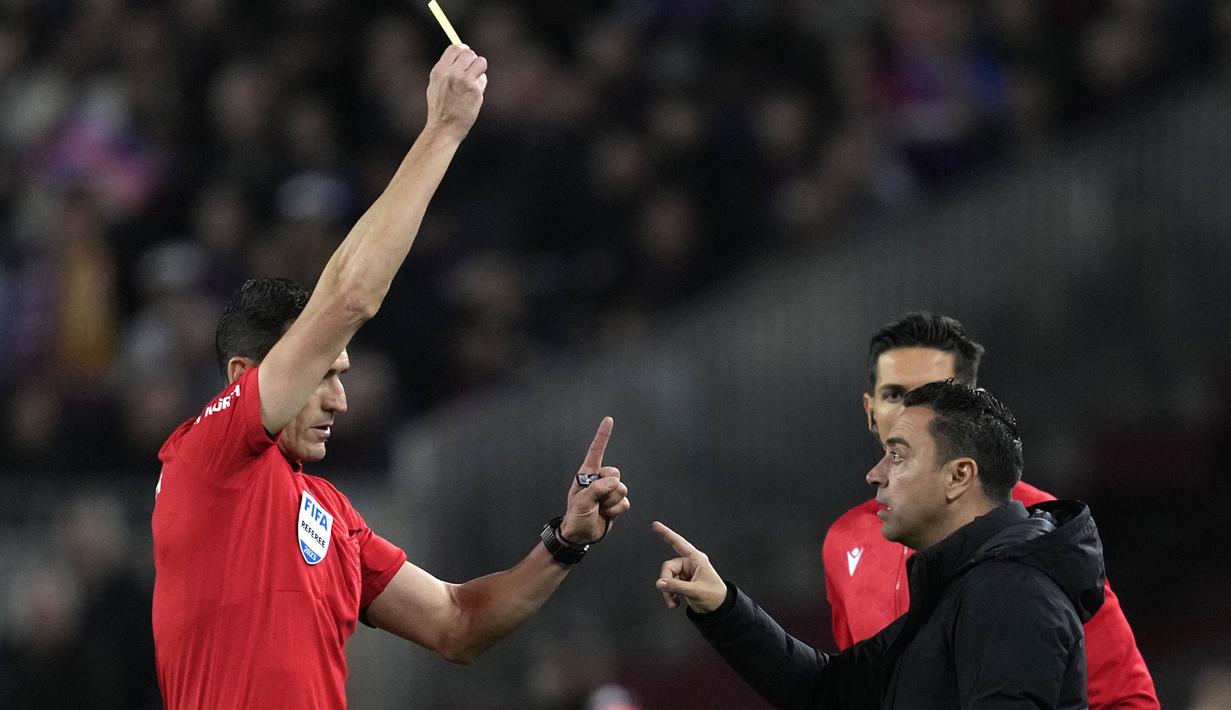 Wasit Juan Martinez Munuera memberikan kartu kuning kepada pelatih Barcelona, Xavi Hernandez saat menghadapi Real Madrid pada laga leg kedua semifinal Copa del Rey 2022/2023 di Camp Nou Stadium, Barcelona, Kamis (6/4/2023) dini hari WIB. (AP Photo/Joan Mateu Parra)