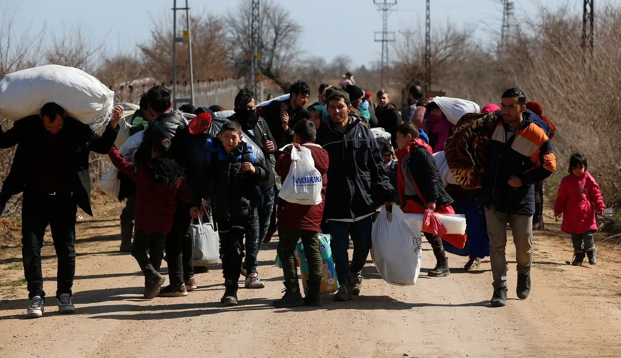 Para migran yang membawa barang-barang berjalan dekat perbatasan Turki dengan Yunani di Gerbang Pazarkule, Edirne, Turki, Selasa (3/3/2020). Turki membuka perbatasannya dengan Yunani setelah eskalasi militer antara pasukan Turki dan Suriah memuncak di barat laut Suriah. (AP Photo/Darko Bandic)