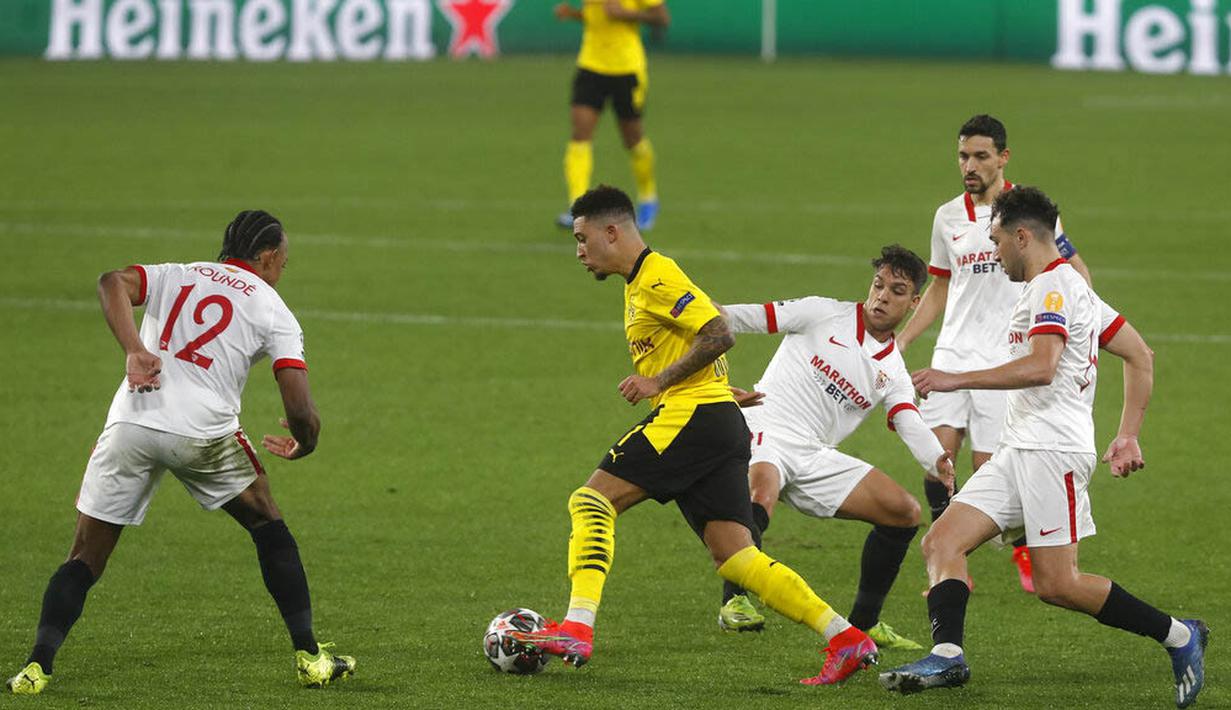 Pemain Borussia Dortmund, Jadon Sancho, melewati pemain Sevilla, Nemanja Gudelj, pada laga Liga Champions di Stadion Ramon Sanchez Pizjuan, Kamis (18/2/2021). Dortmund menang dengan skor 2-3. (AP/Angel Fernandez)