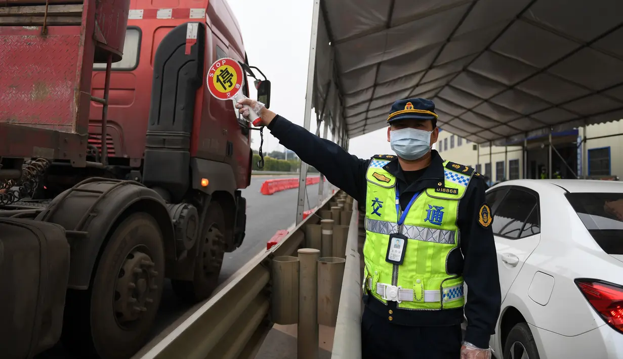 Seorang staf memandu sejumlah kendaraan untuk berhenti di tepi jalan guna mengukur suhu tubuh para pengemudinya di dekat sebuah gerbang tol sebagai upaya memerangi wabah di Nanning, Daerah Otonom Etnis Zhuang Guangxi, China selatan, pada 1 Februari 2020. (Xinhua/Lu Boan)