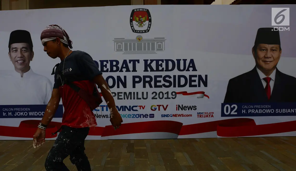 Pekerja melintas di depan baliho debat Capres kedua di Hotel Sultan, Jakarta, Jumat (15/2). KPU mengusung materi debat kedua Capres 2019 mengangkat tema energi, pangan, infrastruktur, sumber daya alam, dan lingkungan hidup. (Merdeka.com/Imam Buhori)