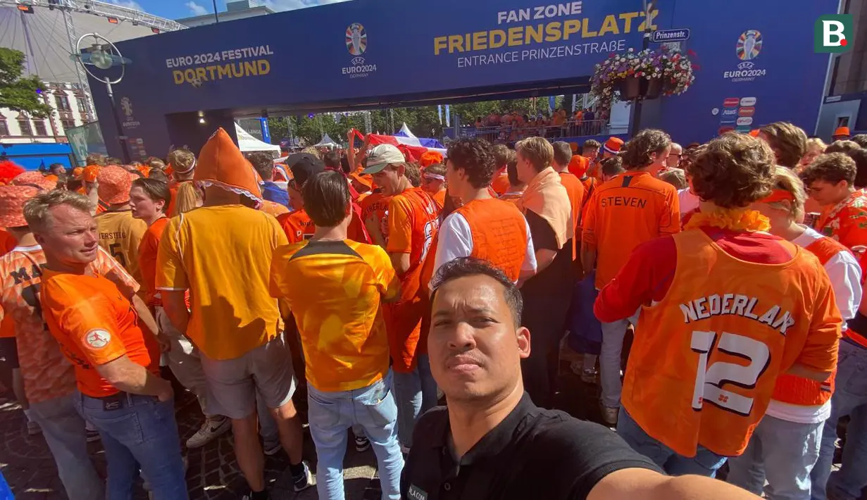 Jurnalis Bola.com, Gerendo Pradigdo di antara fans Belanda di pintu masuk Fan Zone Euro 2024 Friedensplatz di Dortmund, Rabu (10/7/2024) jelang belangsungnya semifinal Euro 2024 antara Belanda menghadapi inggris. (Bola.com/Gerendo Pradigdo)