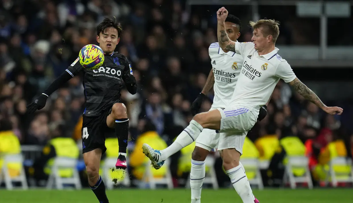 Pemain Real Sociedad, Takefusa Kubo (kiri) berebut bola dengan pemain Real Madrid, Toni Kroos dalam laga La Liga 2022/2023 di Santiago Bernabeu Stadium, Madrid (29/1/2023). Pemain yang sejak awal musim 2022/2023 menjadi milik Real Sociedad setelah didatangkan dari Real Madrid ini kini memiliki nilai pasar senilai 12 juta euro atau setara Rp195 miliar. (AP Photo/Manu Fernandez)