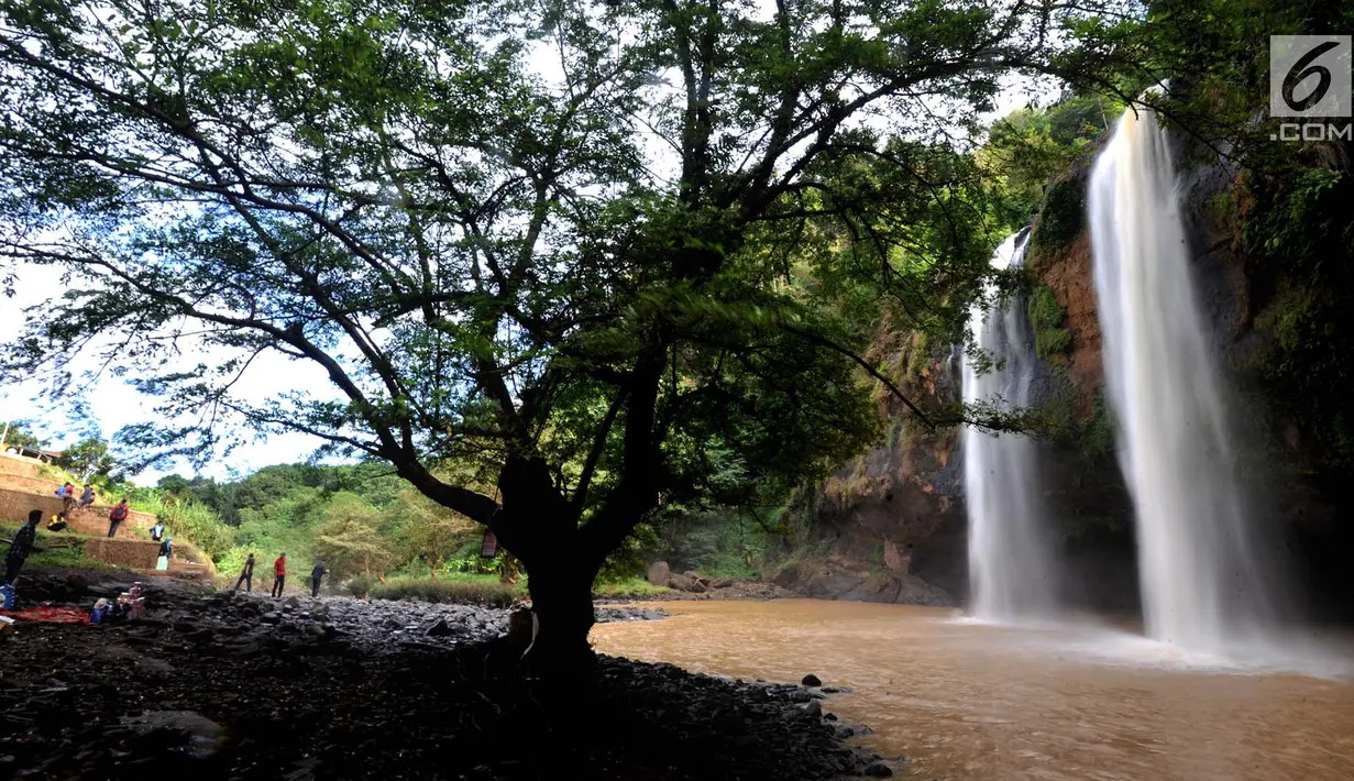 Sejumlah wisatawan menikmati curug Sodong Kembar di kawasan Ciletuh Geopark, Sukabumi, Sabtu (23/6). Tempat ini kian populer karena keindahan alamnya dan batuan alamnya yang dihadirkan di setiap obyek wisata di Geopark Ciletuh. (Merdeka.com/Arie Basuki)