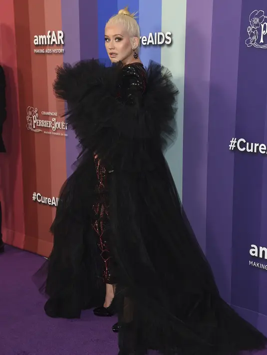 Penyanyi Christina Aguilera berpose saat tiba menghadiri 10th amfAR Gala di Los Angeles, California (11/10/2019). Aguilera tampil anggun dengan gaun hitam serta celana merah berkilau. (AP Photo/Jordan Strauss)