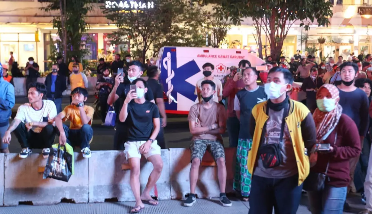 Warga menyaksikan kebakaran yang melanda bagian gedung di Kompleks Kejaksaan Agung Republik Indonesia, Sabtu (22/8/2020) malam. Hingga berita ini diturunkan, petugas masih berjibaku memadamkan api agar tidak menjalar ke gedung-gedung sebelahnya. (Liputan6.com/Herman Zakharia)