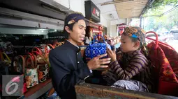 PKL bermain dengan seorang anak di emperan toko kawasan Malioboro mengenakan pakaian tradisional, Rabu (20/4/2016). Sejumlah PKL mengenakan pakain adat jawa menyambut hari Kartini 21 April besok. (Liputan6.com/Boy Harjanto)