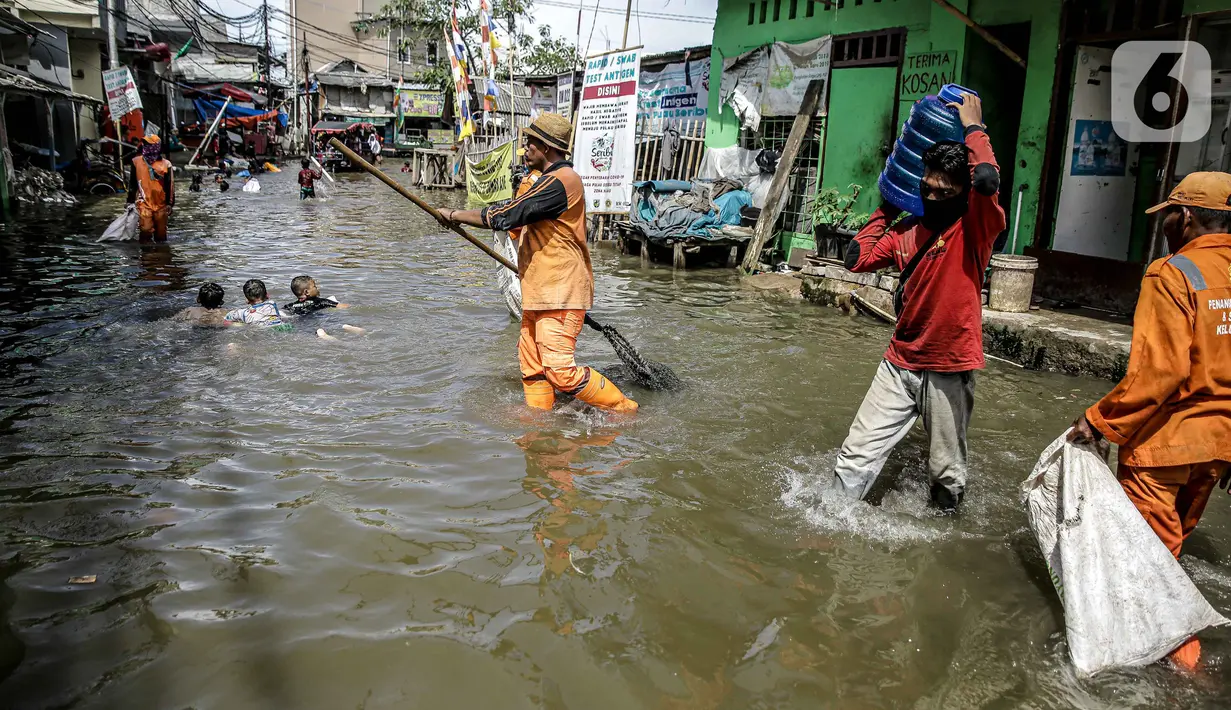 Petugas PPSU membersihkan sampah saat terjadi banjir rob di Pelabuhan Kali Adem, Muara Angke, Jakarta, Selasa (9/11/2021). Walau terendam banjir rob, petugas PPSU tetap sigap bersihkan sampah yang mengambang terbawa air laut. (Liputan6.com/Faizal Fanani)