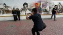 Sejumlah pengunjung berpose di dekat gambar Raja Bhumibol Adulyadej yang terpasang di Grand Palace di Bangkok, Thailand, Rabu (19/10). Untuk menghormati Raja Bhumibol Adulyadej, Grand Palace dipasangi gambarnya. (REUTERS / Chaiwat Subprasom)