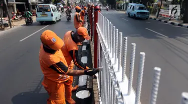 Petugas PPSU Kelurahan Kramat Jati melakukan pengecatan ulang pagar pembatas Jalan Raya Bogor, Jakarta, Selasa (17/7). Upaya penataan sekaligus mempercantik kawasan terus dilakukan jelang Asian Games dan Hari Kemerdekaan RI. (Liputan6.com/Arya Manggala)