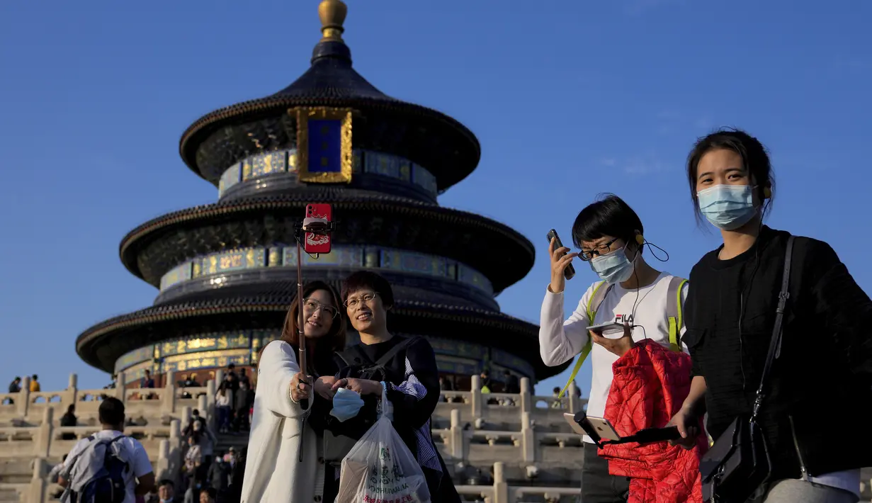 Para wanita berfoto selfie saat pengunjung mengunjungi Kuil Surga pada hari terakhir Hari Nasional China selama seminggu di Beijing, Kamis (7/10/2021). (AP Photo/Andy Wong)