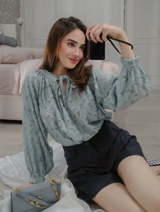 Selanjutnya, Syifa mengenakan atasan lengan panjang dengan tali depan warna hijau bertekstur. Dipadukan celana pendek hitam sambil membawa tas warna abu-abu. [@syifahadju]