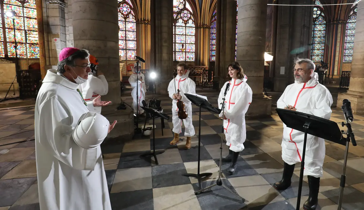 Uskup Agung Paris Michel Aupetit (kiri) berbicara dengan pemain biola Renaud Capucon, aktris Judith Chemla, dan aktor Philippe Torreton saat perayaan Jumat Agung selama pandemi virus corona COVID-19 di Katedral Notre-Dame de Paris, Prancis, Jumat (10/4/2020). (Ludovic Marin, Pool via AP)