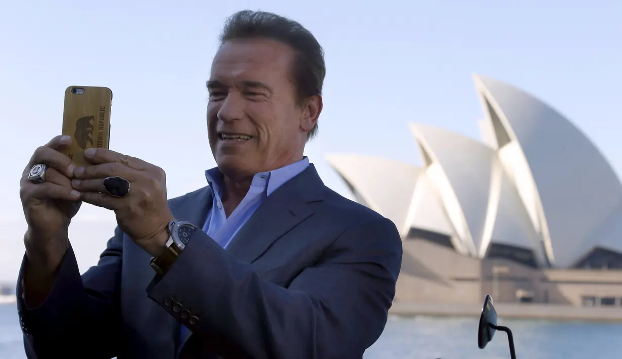 Mantan Gubernur California, Arnold Schwarzenegger melakukan selfie saat mempromosikan film terbarunya, `Terminator Genisys` di depan Sydney Opera House di Australia, Kamis (4/6/2015). Film tersebut disutradai oleh Alan Taylor. (REUTERS/David Gray)