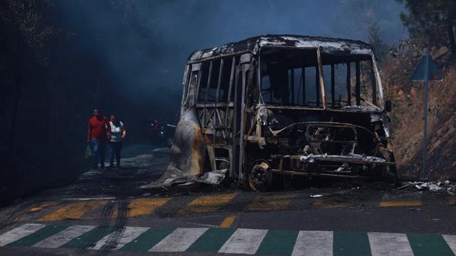 Warga berjalan melewati kendaraan yang hangus terbakar di sebuah jalan di Cointzio, Negara Bagian Michoacan, Meksiko, Minggu, (22/2/2026). Kendaraan tersebut dibakar menyusul tewasnya pemimpin Kartel Narkoba CJNG El Mencho.kha