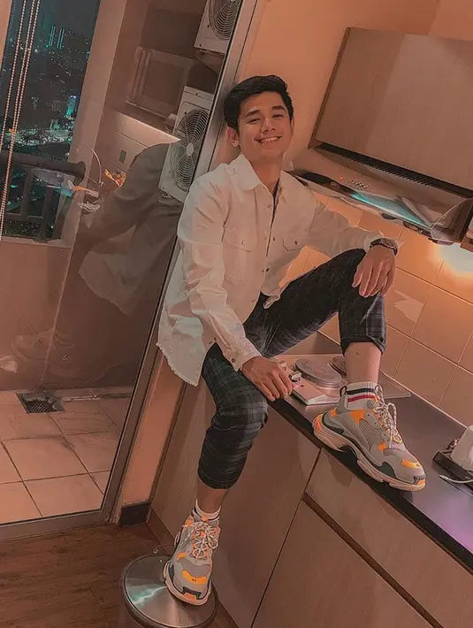 Tak melulu kenakan hoodie, kadang kala Rayn pun mengenakan kemeja. Dalam foto ini, Rayn memadukan kemeja putih, celana tartan berwarna hitam, serta sepatu sneakers yang membuatnya terlihat sedikit sporty. (Liputan6.com/IG/raynwijaya26)