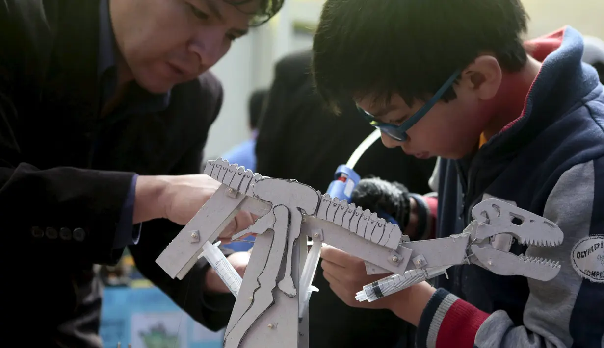 Seorang anak sedang mereparasi robotnya pada olimpiade sains di La Paz , Bolivia,  Senin (10/8/2015). 150 robot dipamerkan disini dan dipilih siapa yang terbaik. (REUTERS/David Mercado)