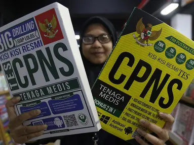 Pekerja menunjukkan buku di Pasar Kenari, Jakarta, Kamis (28/11/2019). Buku panduan lolos tes yang dijual mulai dari Rp 88.000 hingga Rp 195.000 per eksemplar menjadi barang yang paling dicari dan diminati jelang pelaksanaan tes CPNS. (Liputan6.com/Herman Zakharia)