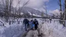 Tim petugas kesehatan dan dokter membawa vaksin saat mereka berjalan di jalan yang tertutup salju selama upaya vaksinasi COVID-19 di Budgam, barat daya Srinagar, Kashmir yang dikuasai India, pada 11 Januari 2022. (AP Photo/Dar Yasin)