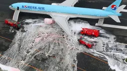 Gambar udara menunjukkan sejumlah penumpang berdiri di dekat pesawat Korean Air Lines setelah asap keluar dari bagian mesin sebelah kiri itu di bandara Haneda di Tokyo, Jepang, (27/5). (Reuters/ Kyodo)
