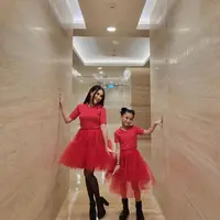 Ibu dan anak ini kembaran pakai dress tulle merah yang dipadukan sepatu boots hitam.