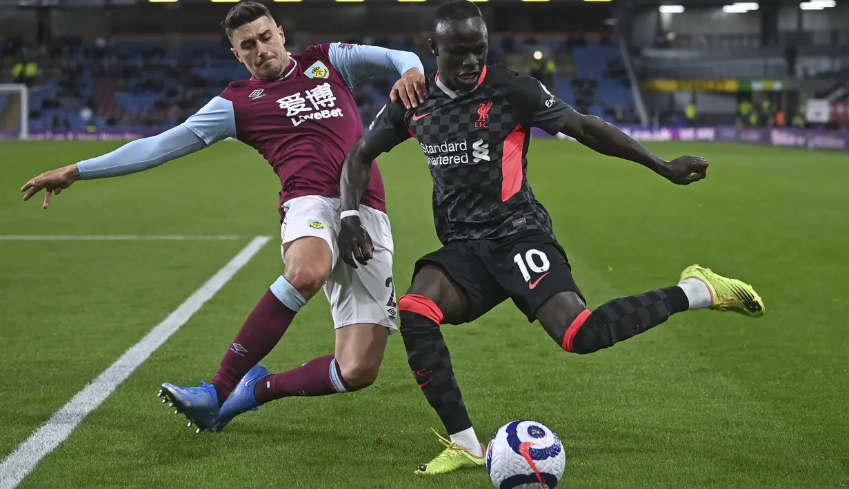 Bek Burnley, Matthew Lowton bersaing dengan penyerang Liverpool, Sadio Mane pada pekan ke-37 Liga Inggris di Stadion Turf Moor, Kamis (20/5/2021) dini hari WIB. Liverpool sukses menembus empat besar klasemen Liga Inggris setelah menang telak 3-0 atas Burnley. (Gareth Copley/Pool via AP)