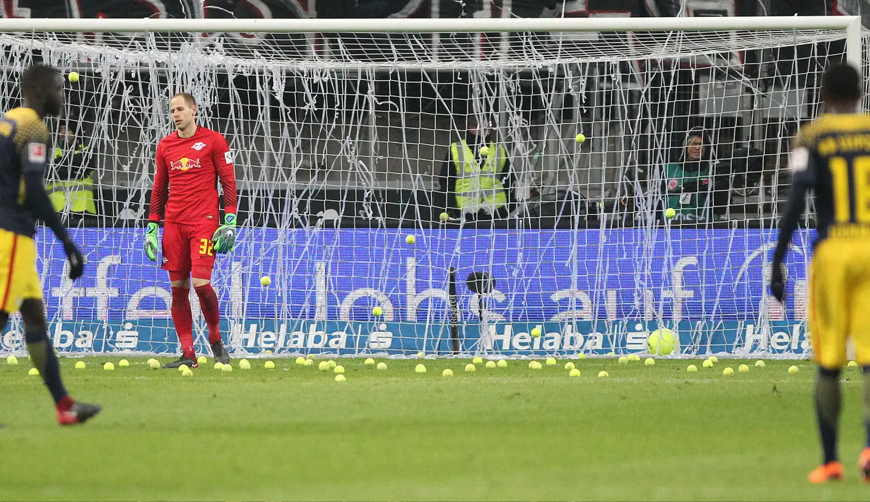 Suporter melempar bola tenis ke lapangan saat Kick-off  laga Eintracht Frankfurt vs RB Leipzig di Stadion Commerzbank Arena, Senin (19/2). Aksi tersebut membuat pertandingan Bundesliga 1 pekan ke-23 harus mengalami dua kali penundaan. (DANIEL ROLAND/AFP)