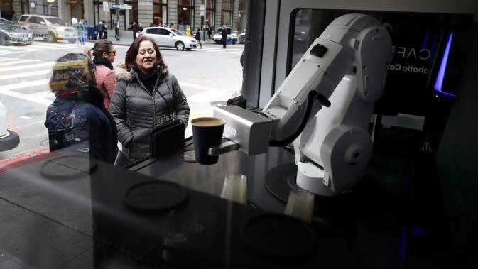 Pelanggan menyaksikan robot barista membuat kopi di Cafe X, San Francisco, California, AS, Selasa (12/2). Cafe X menggunakan robot untuk menyajikan makanan dan minuman. (Justin Sullivan/Getty Images/AFP)