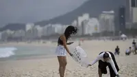 Dua wanita memungut sampah dari pantai Copacabana pada Hari Laut Sedunia di Rio de Janeiro, Brasil, Rabu (8/9/2022). Organisasi Route Brasil menyerukan agar orang-orang berkumpul untuk acara yang diberi nama "Pelukan Itu," dan untuk memungut sampah di pantai, untuk menarik perhatian pada pencemaran laut. (AP Photo/Silvia Izquierdo)