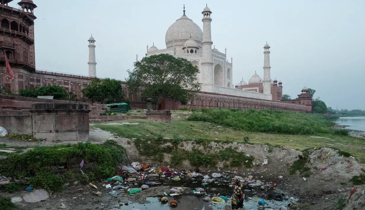 Pemandangan Taj Mahal dari seberang parit di tepi sungai Yamuna, Agra, India, Jumat (4/5). Kini, warna Taj Mahal  yang seharusnya putih marmer berubah menjadi kuning bahkan cokelat dan hijau di sejumlah sisinya. (AFP/CHANDAN KHANNA)