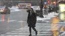 Seorang wanita melintasi Jalan Walker Chicago selama badai salju, Kamis (4/2/2021).  Total salju mengantarkan suhu di bawah titik beku di belakangnya di wilayah Chicago yang lebih luas. (AP Photo/Shafkat Anowar)