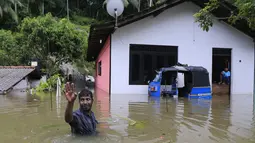 Seorang warga melambaikan tangan di dekat rumahnya yang dilanda banjir, Sri Lanka, Minggu (28/5). Atas bencana banjir dan longsor ini, Kementerian Luar Negeri Sri Lanka telah mengajukan permintaan bantuan dari PBB dan negara-negara tetangga. (AP Photo)