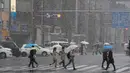 Warga menggunakan payung berjalan selama hujan salju lebat di Tokyo (22/1). Hujan salju membuat keberangkatan penerbangan dan melumpuhkan beberapa layanan kereta api di kota tersebut. (AP Photo/Shizuo Kambayashi)