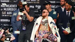 Ekspresi Conor McGregor saat dilemparkan uang petinju Floyd Mayweather saat konferensi pers tur dunia jelang pertandingannya di Barclays Center, Brooklyn, (13/7). Duel ini akan digelar di Las Vegas pada 26 Agustus. (Mike Stobe/Getty Images/AFP)