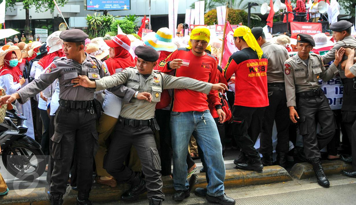 Personel kepolisian berusaha menahan para bidan desa yang berupaya menutup akses jalan saat demonstrasi di depan gedung Kemenkes, Jakarta, Rabu (4/5). Para bidan menuntut diangkat menjadi pegawai tetap tanpa syarat.  (Liputan6.com/Yoppy Renato)