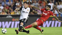 Striker Valencia, Santi Mina, berebut bola dengan gelandang Sevilla, Ever Banega, pada laga La Liga Spanyol di Stadion Mestalla, Sabtu (21/10/2017). Valencia menang 4-0 atas Sevilla. (AFP/Jose Jordan)