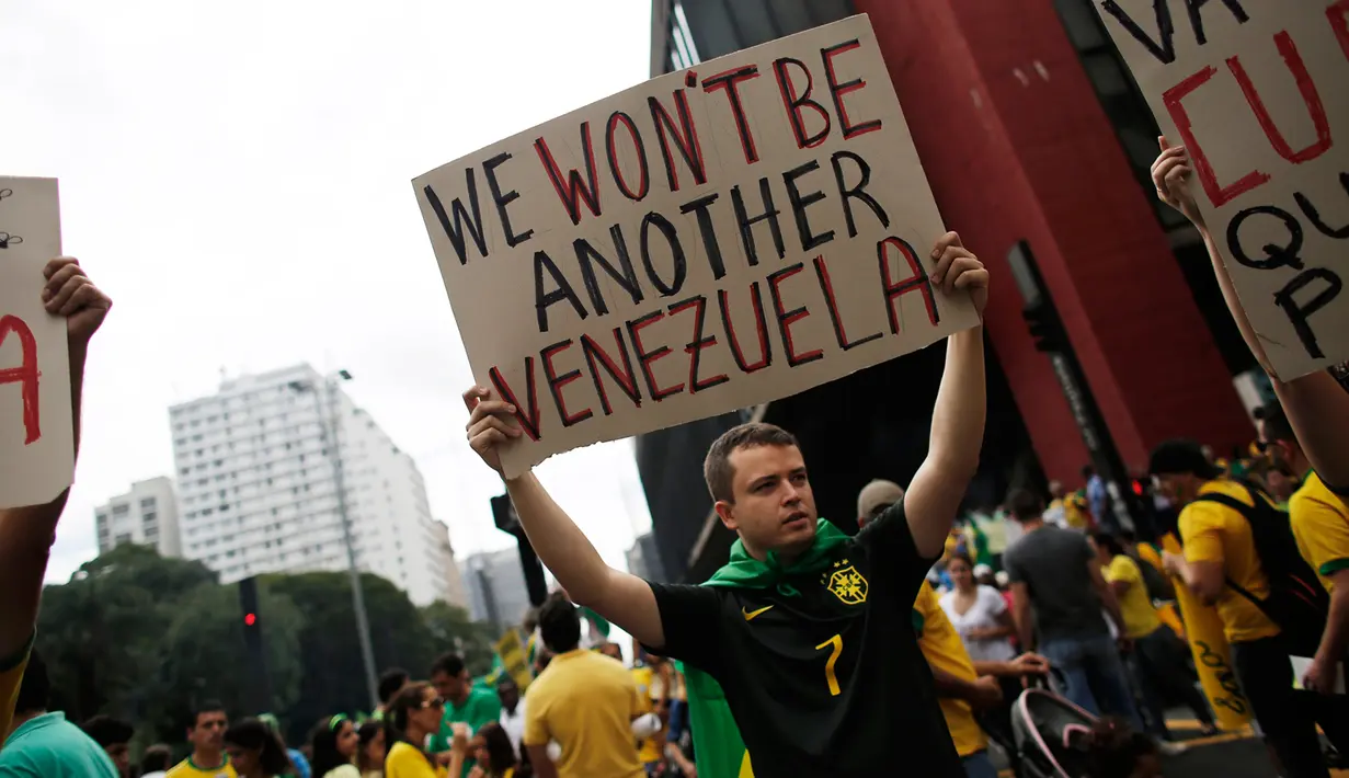 Seorang demonstran membawa tulisan memprotes Presiden Brazil Dilma Rousseff, Sao Paulo, Brazil (15/3/2015). Satu juta demonstran memenuhi ruas jalan di kota-kota Brazil untuk memprotes ekonomi lesu, kenaikan harga dan korupsi.  (Reuters/Nacho Doce)