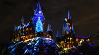 Cahaya warna-warni menghiasi kastil Dunia Harry Potter dihiasi cahaya biru di Universal Studios Hollywood, Universal City (16/11). Pertunjukan ini bertemakan 'The Magic of Christmas at Hogwarts Castle'. (AFP Photo/Chris Delmas)