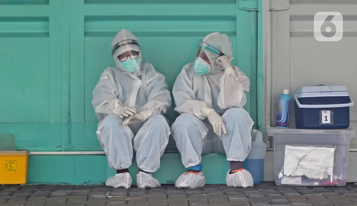 Tenaga kesehatan dengan APD menunggu warga yang akan melakukan tes swab di sekitar GSI Lab (Genomik Solidaritas Indonesia Laboratorium), Jakarta, Sabtu (3/10/2020). Pemerintah telah menyepakati batas maksimal harga tes usap atau swab mandiri sebesar Rp900 ribu. (Liputan6.com/Herman Zakharia)
