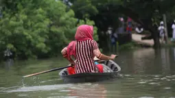 Seorang pria mendayung rakit mengarungi area banjir di Munshiganj, pinggiran Dhaka, Bangladesh, Senin (27/7/2020). Hingga 27 Juli 2020, hampir separuh dari wilayah Bangladesh masih terendam banjir. (Xinhua)