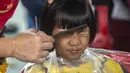Seorang anak mengikuti cukur rambut gratis saat acara amal di Surabaya, Jawa Timur, Senin (8/11/2021). Layanan cukur rambut gratis ini dilakukan kepada 100 anak yatim piatu. (Juni Kriswanto/AFP)
