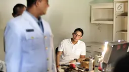 Wakil Gubernur DKI Jakarta terpilih Sandiaga Uno mengamati Gubernur DKI Jakarta terpilih Anies Baswedan yang bersiap untuk pemotretan dengan pakaian dinas upacara (PDU) di kawasan Kebayoran Baru, Jakarta, Kamis (12/10). (Liputan6.com/Pool/Tim Anies-Sandi)