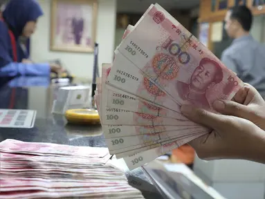 Seorang teller menunjukan  mata uang Yuan di Jakarta, Senin (30/11). Dana Moneter Internasional (IMF), Senin (30/11), resmi memasukan yuan, atau renminbi, ke dalam special drawing rights (SDR) sebagai mata uang elite dunia. (Liputan6.com/Angga Yuniar)