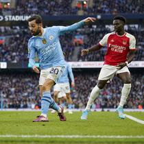 Gelandang Manchester City, Bernardo Silva (tengah) melepaskan umpan yang berusaha diblok bek Arsenal, Ben White pada laga pekan ke-30 Premier League 2023/2024 di Etihad Stadium, Manchester, Minggu (31/3/2024). (AP Photo/Dave Thompson)