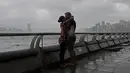 Warga berciuman saat angin kencang yang disebabkan oleh angin topan Hato menerjang tepi pantai Victoria Habour di Hong Kong, (23/8). Terjangan topan Hato mengakibatkan lebih dari 400 penerbangan dibatalkan. (AP Photo/Vincent Yu)