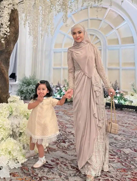 Hadir bersama Moana, Ria Ricis terlihat anggun dalam balutan dress berpayet warna nude dari @mawaddatulhaq yang dipadukan dengan pashmina dengan aksen bunga cantik di kepala. [@riaricis1795].