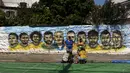 Pemandangan saat warga melukis mural Piala Dunia 2018 bergambar para pemain Brasil di dinding jalanan Camboata, Rio de Janeiro, Brasil, Kamis (31/6). (Fabio TEIXEIRA/AFP)