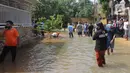 Warga memantau banjir akibat jebolnya tanggul karena tertimpa tanah longsor, di Perumahan Nerada Estate Ciputat, Tangerang Selatan, Sabtu (12/6/2021). Longsor yang menimpa sejumlah rumah membuat tanggul pembatas kali jebol dan air meluap sehingga menyebabkan banjir. (Liputan6.com/Angga Yuniar)